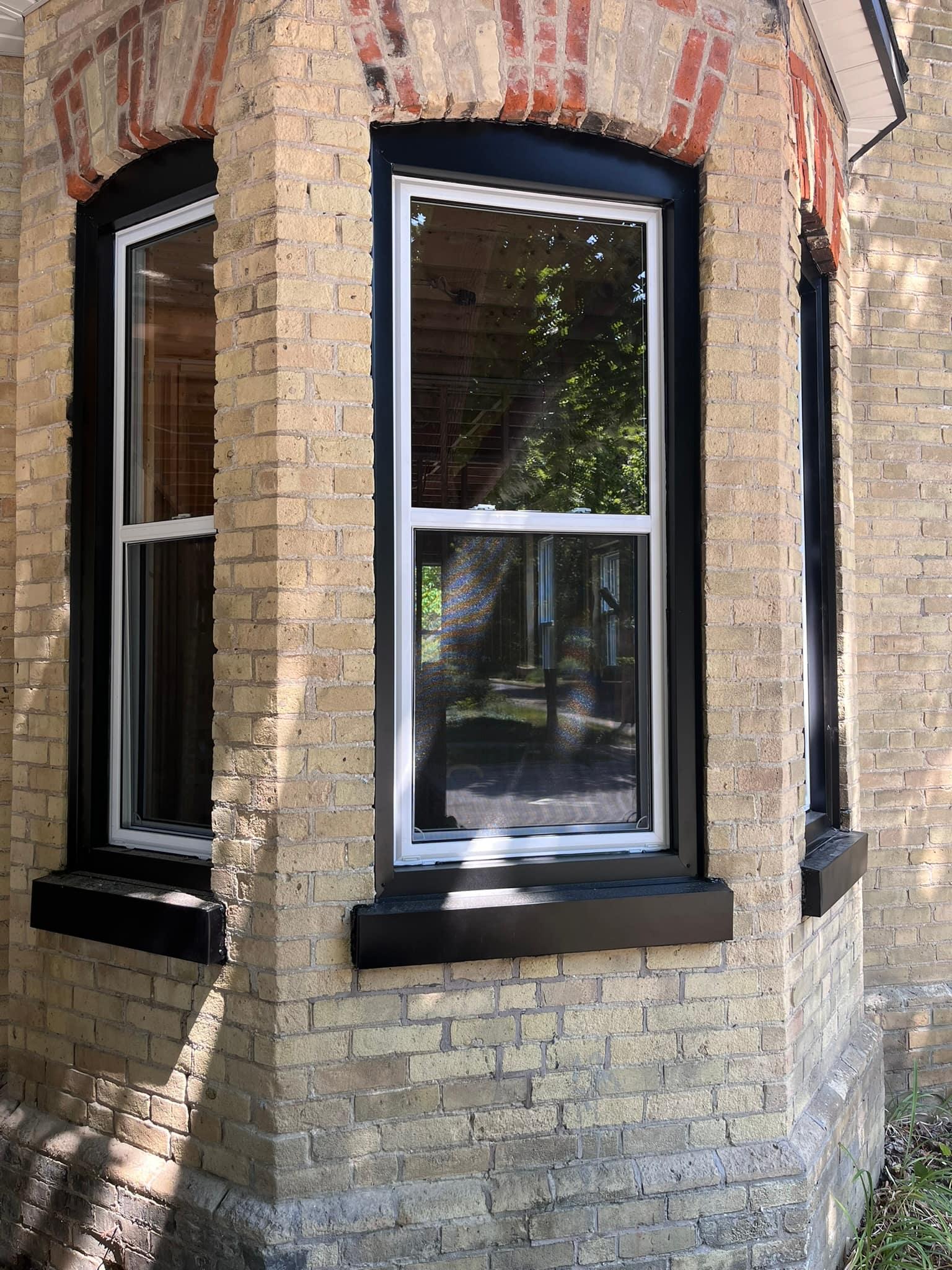 Black-frame replacement windows in a yellow-brick bay